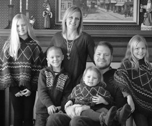 Andrea, her husband, and four children sit in front of the fireplace during the holidays.