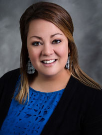 woman wearing black blazer with blue shirt smiling at camera