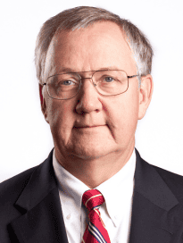 A photo of Dr. Michael Dehning in a black suit coat with a white shirt and red tie.