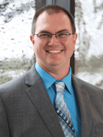 Photo of Dr. Egertsen in a blue shirt and grey blazer with a white tie